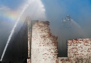 Fire crews douse the collapsed roof of a historic building in downtown Scott City after a fire broke out shortly after 1 p.m. The building located on the 400 block of Main Street was home to BraunÕs Butcher Block. Fire departments from several counties responded to the blaze and continued to work through the evening to put out hot spots.